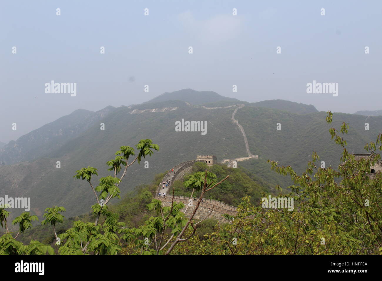 La Grande Muraglia della Cina al Mutyanu. Mountanious paesaggio con lo smog da Pechino in background Foto Stock