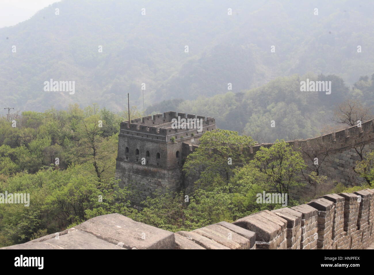 La Grande Muraglia della Cina al Mutyanu. Mountanious paesaggio con lo smog da Pechino in background Foto Stock