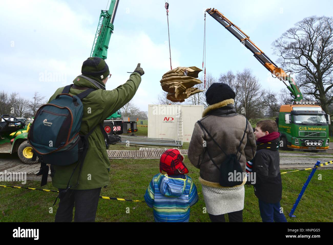 Una famiglia guardare Yorkshire Sculpture Park i tecnici che installano un 7 tonnellata di scultura in bronzo dello scultore Tony Cragg. Foto Stock