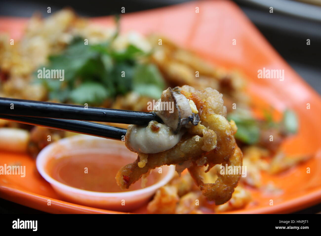 Oyster omelette o Orh Luak. Popolari hawker / notte alimentare sul mercato di Singapore. Guarnite con foglie di coriandolo e servite con salsa di peperoncino. Foto Stock