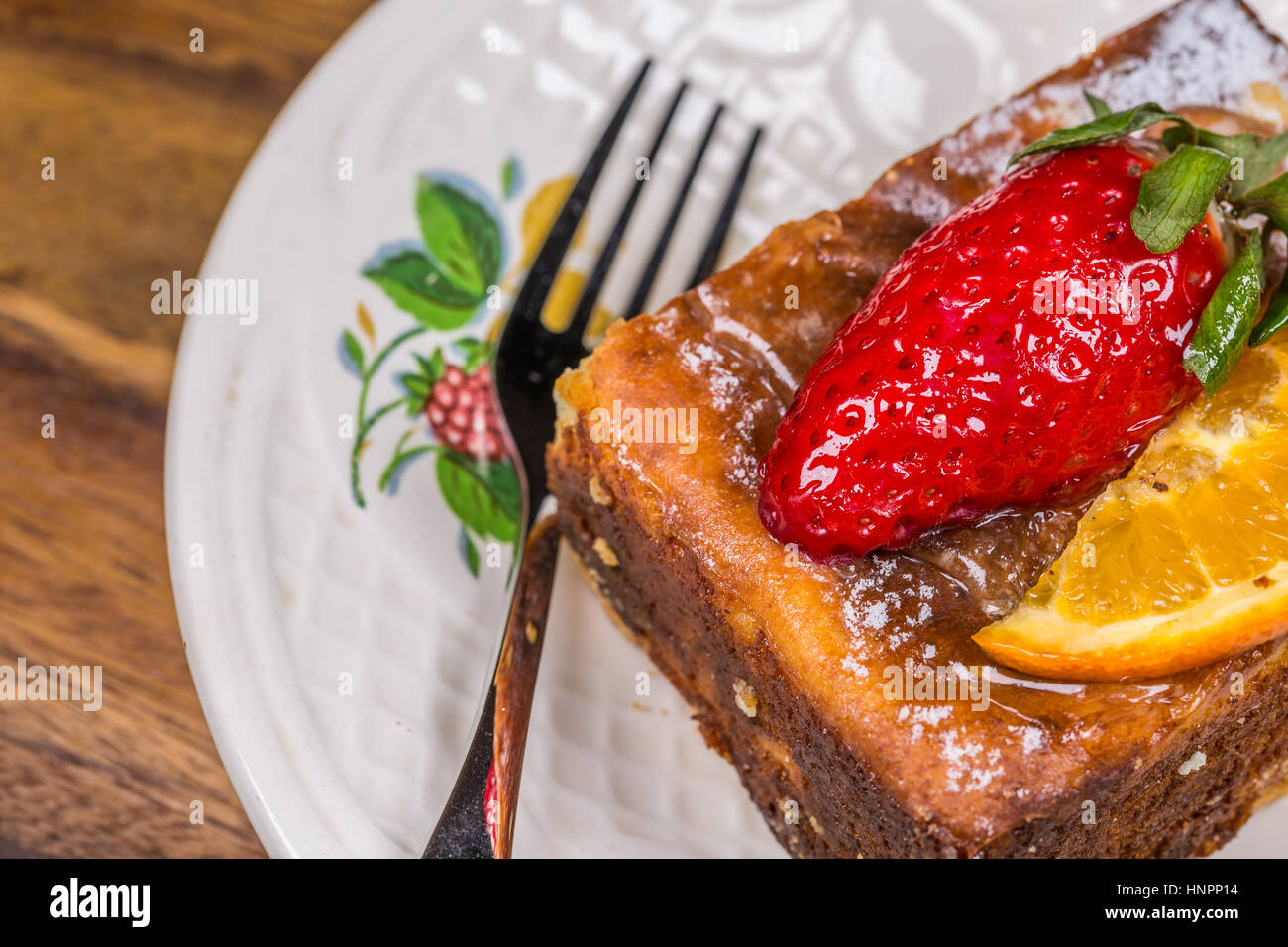 Pezzo di torta di frutta con fragola e limone sul piattino con forcella sul tavolo di legno Foto Stock