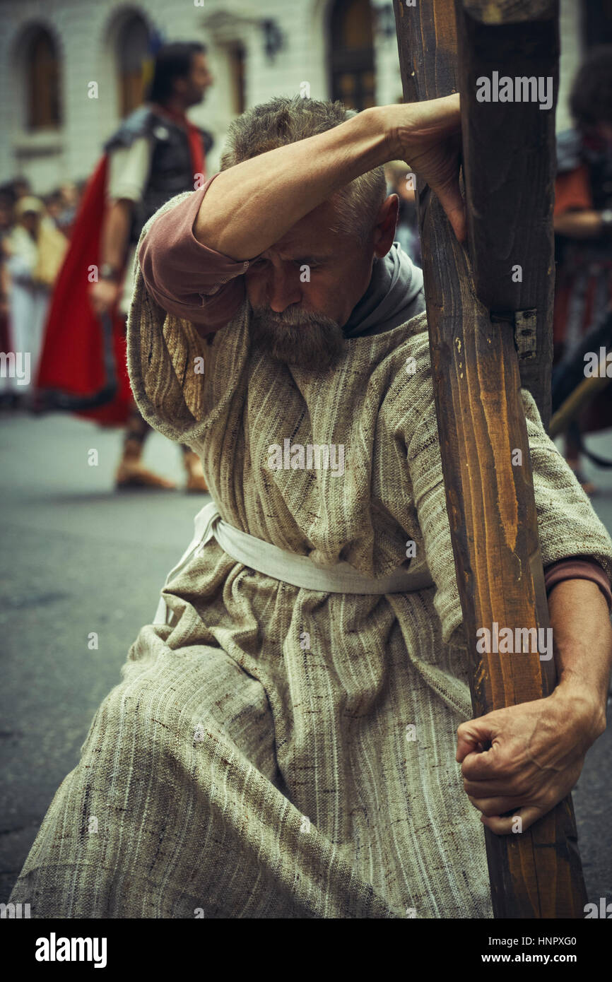 L'uomo che agisce come seguace di Gesù porta la croce durante la messa in scena di strada delle Stazioni della Croce del Venerdì Santo, 15 aprile 2014, Bucarest, Romania Foto Stock