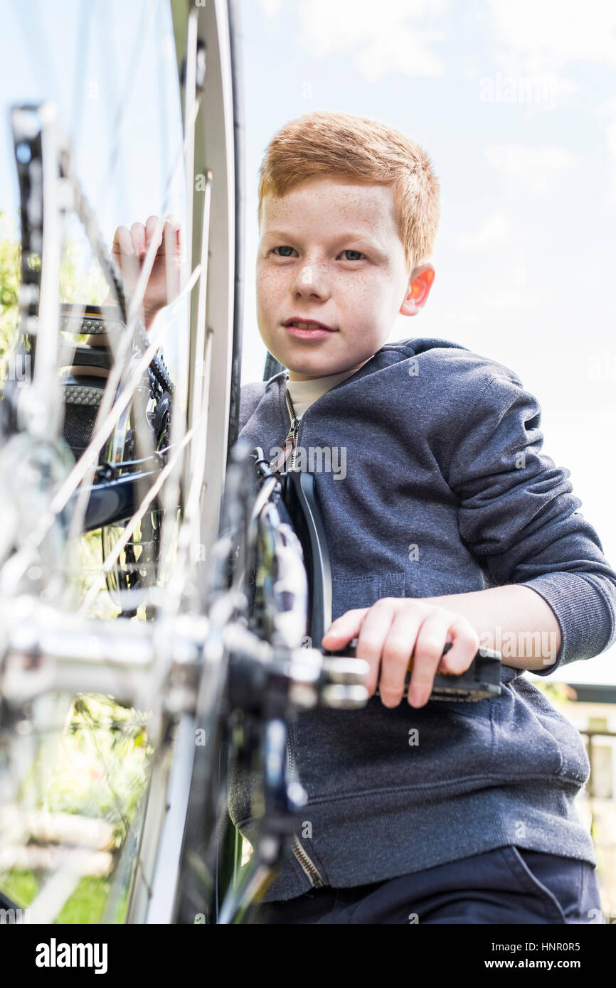 Un ragazzo mantenendo la sua bici Foto Stock