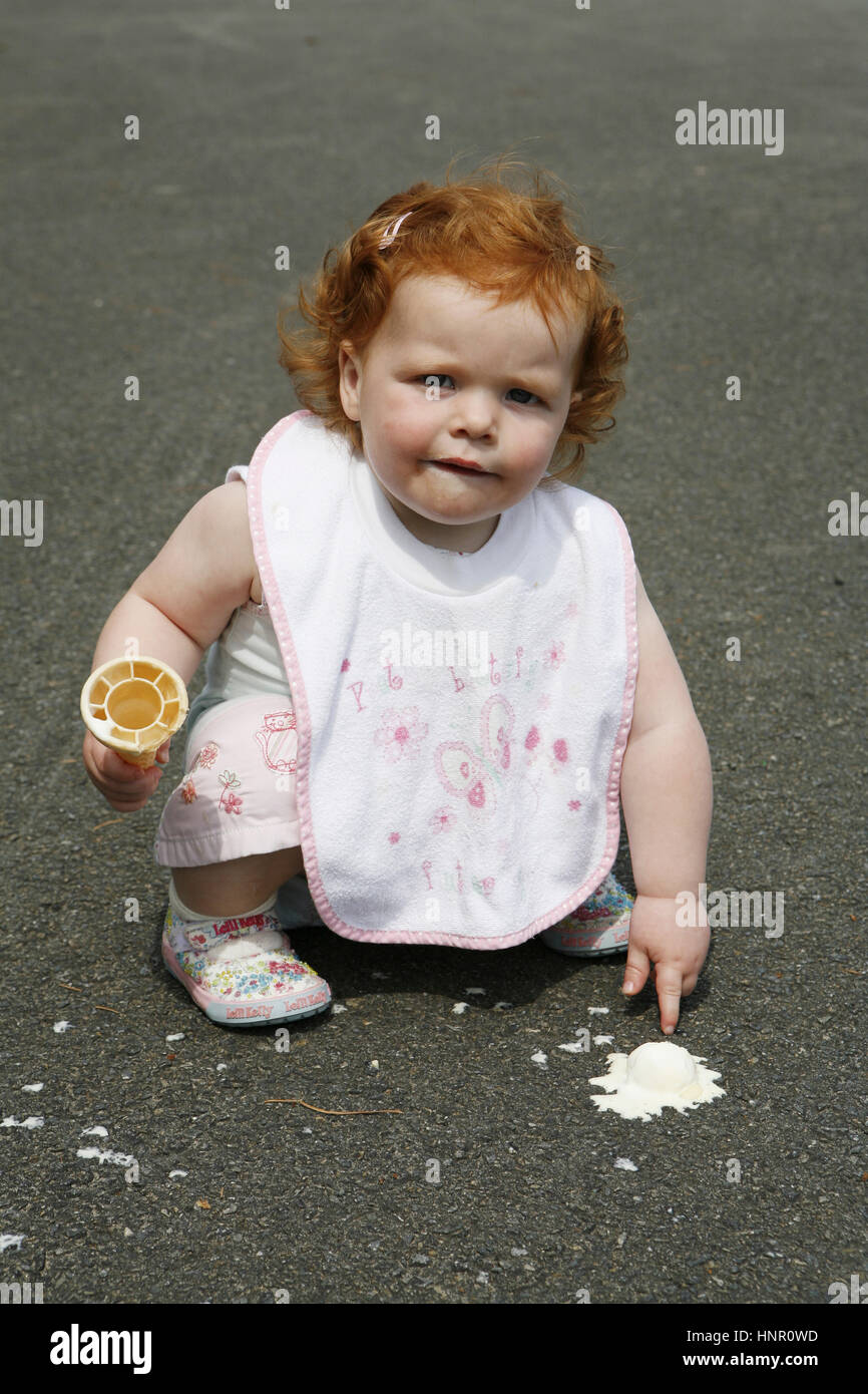 Bambina con il suo gelato che ha lasciato cadere sul pavimento Foto Stock