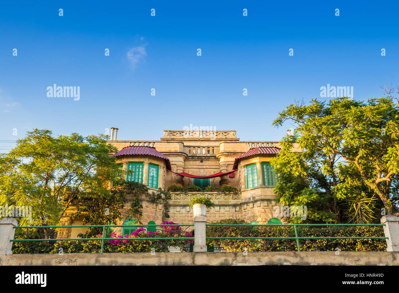 Msida, Malta - tradizionale vecchio edificio maltese in Msida con cielo blu e alberi e fiori Foto Stock
