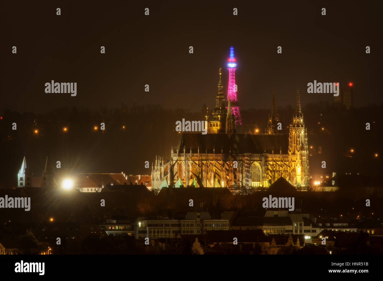 Il Petrin Lookout Tower in Praga illuminata con il tricolore con il castello di Praga nella parte anteriore. Bella notte paesaggio urbano Foto Stock
