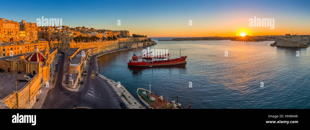 La Valletta, Malta - panoramica vista sullo skyline di La Valletta e il Grand Harbour con bellissima alba, navi e cielo blu chiaro Foto Stock