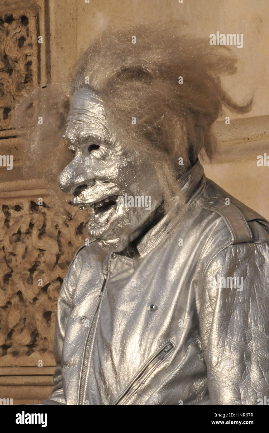 L'artista di strada con una maschera facciale e vestiti ricoperto in argento dipinto. Foto Stock