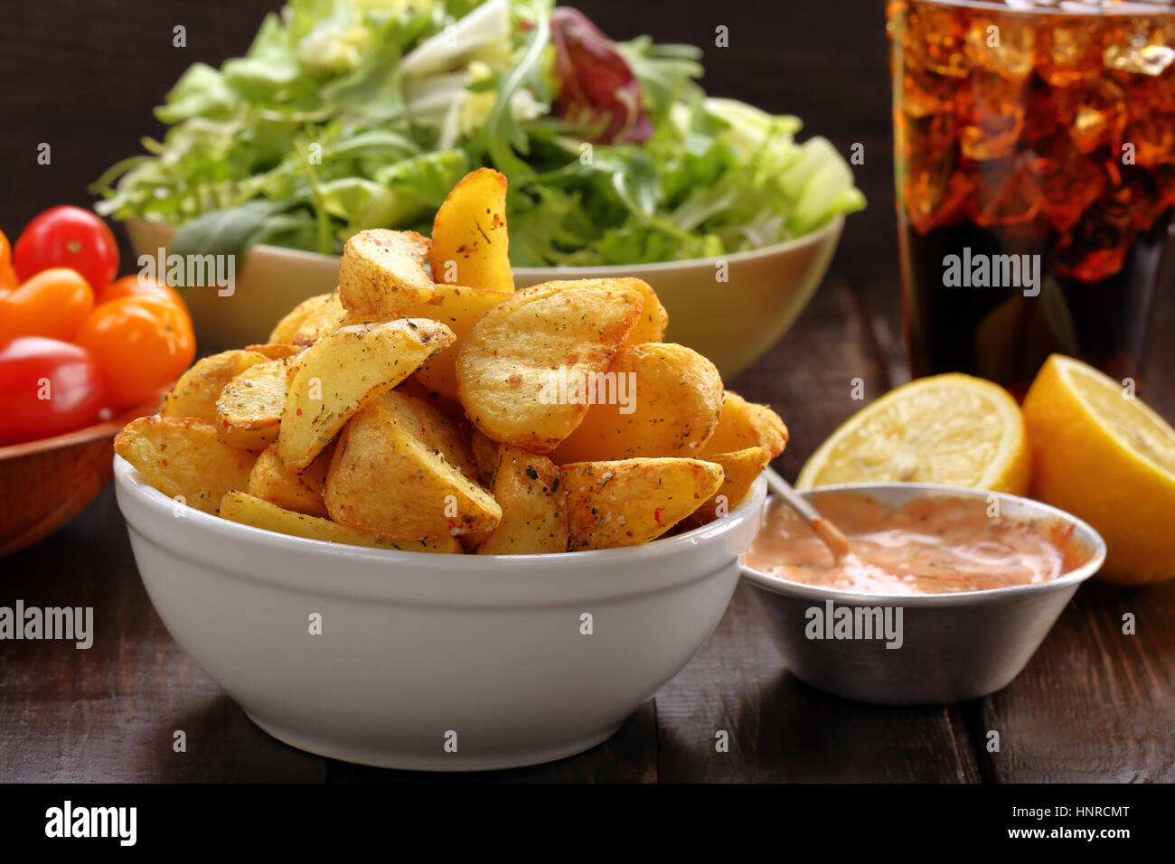 Patate arrosto con dip e insalata fresca sul tavolo di legno Foto Stock