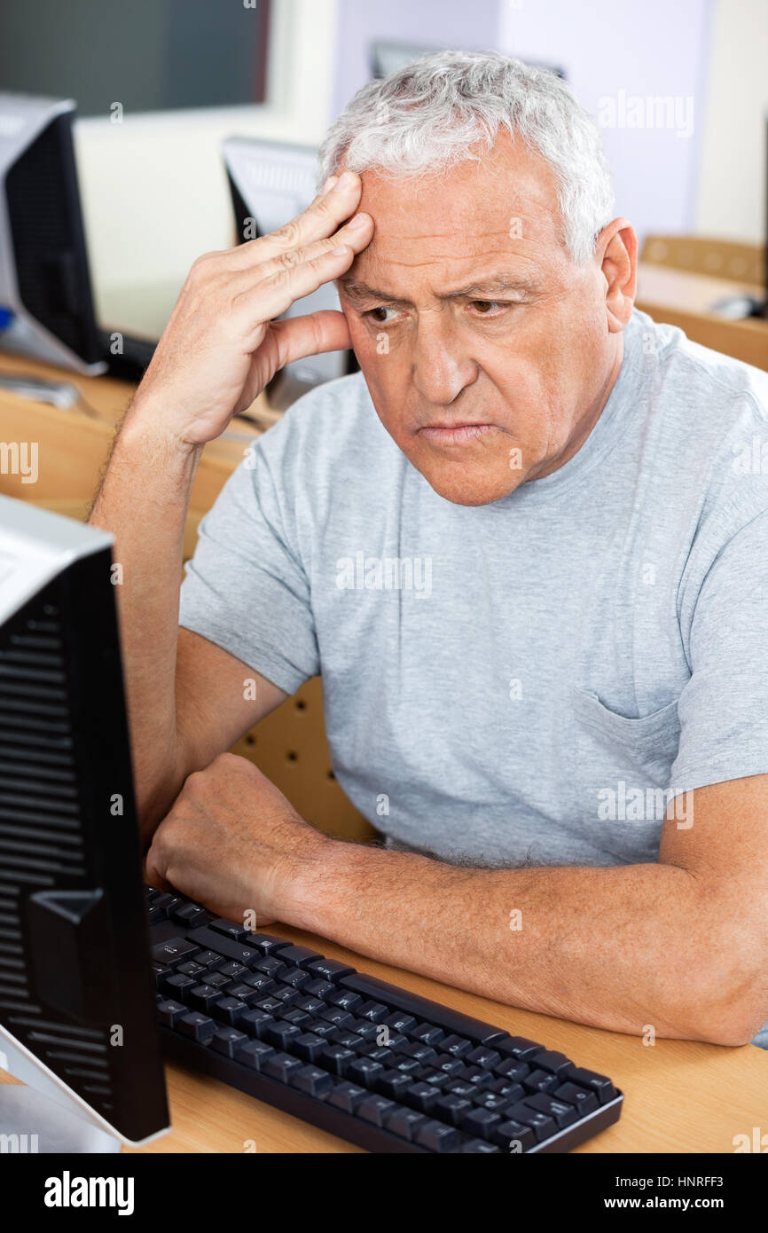 Sottolineato anziano studente guardare il computer Foto Stock