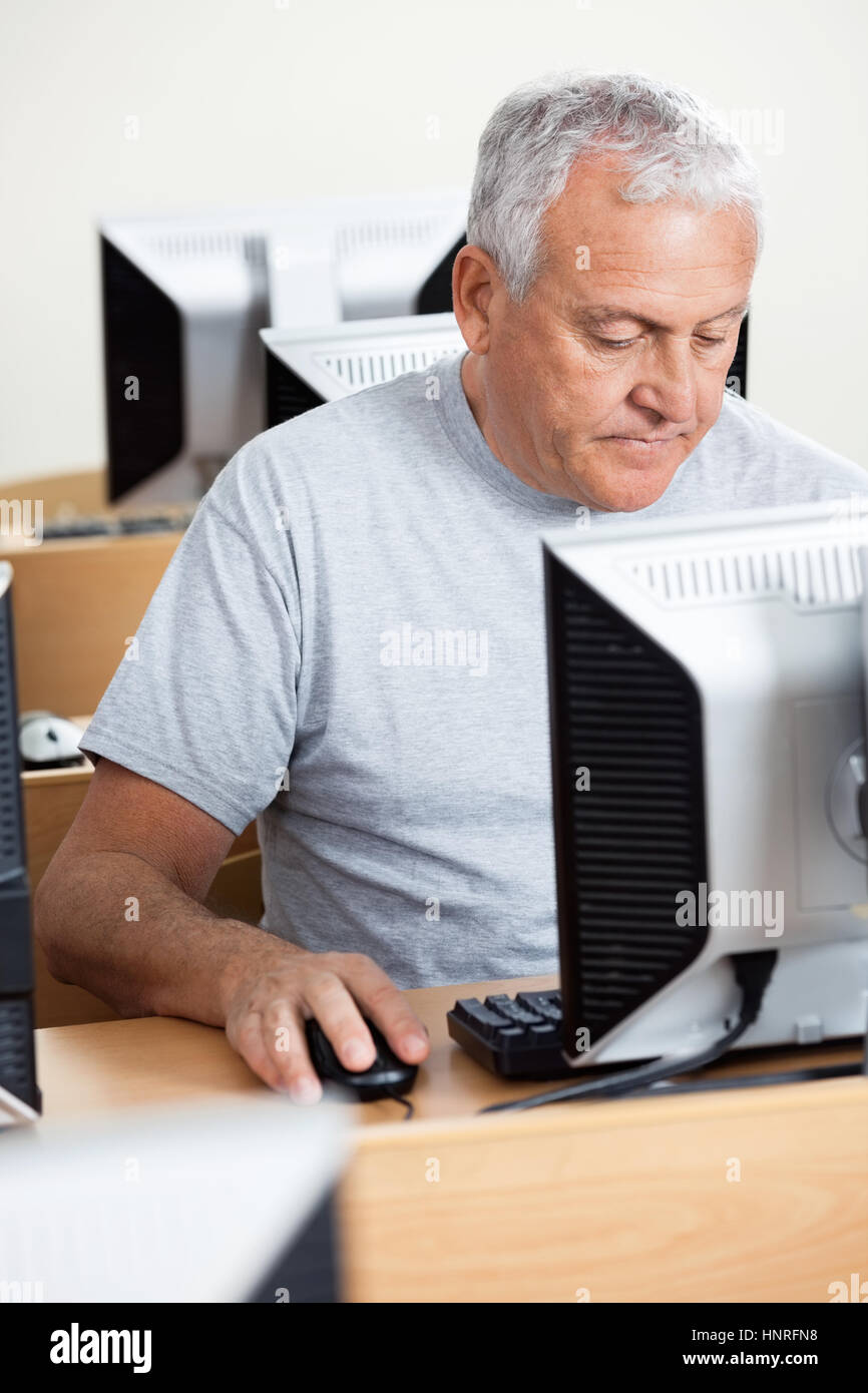 Senior uomo tramite il computer al banco in aula Foto Stock