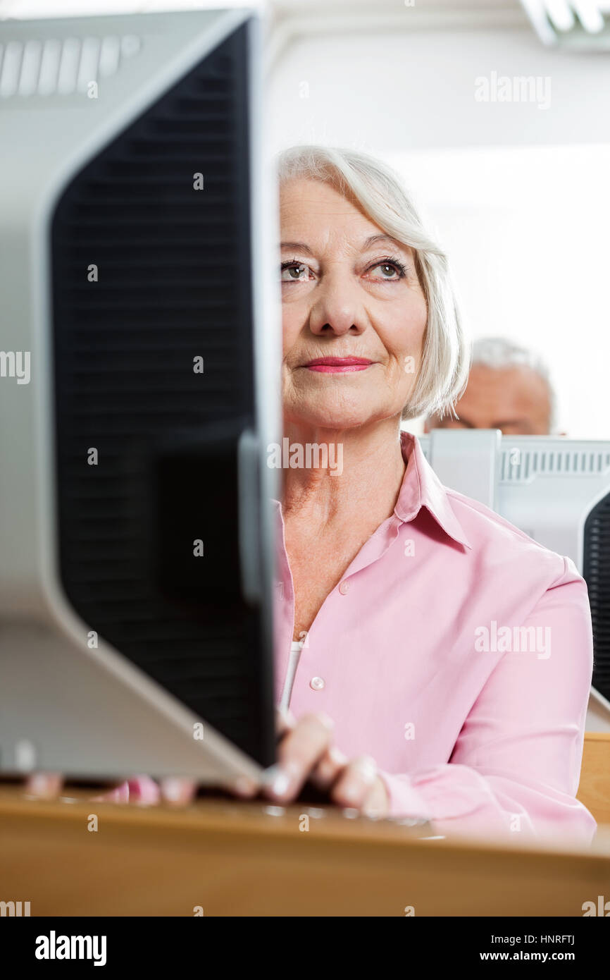 Premurosa donna senior utilizzando computer in aula Foto Stock