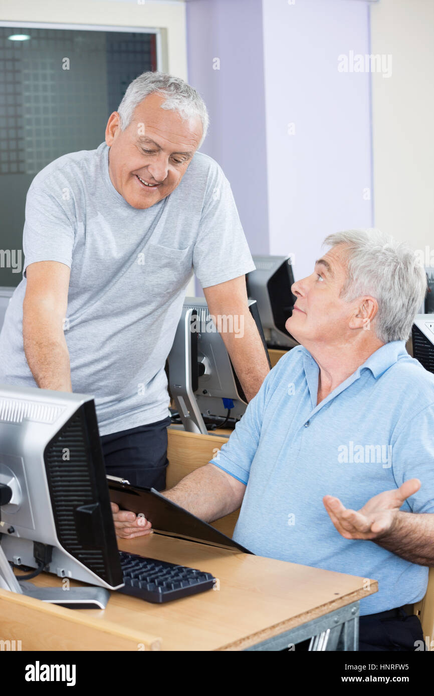 Alti uomini avente la discussione in classe computer Foto Stock