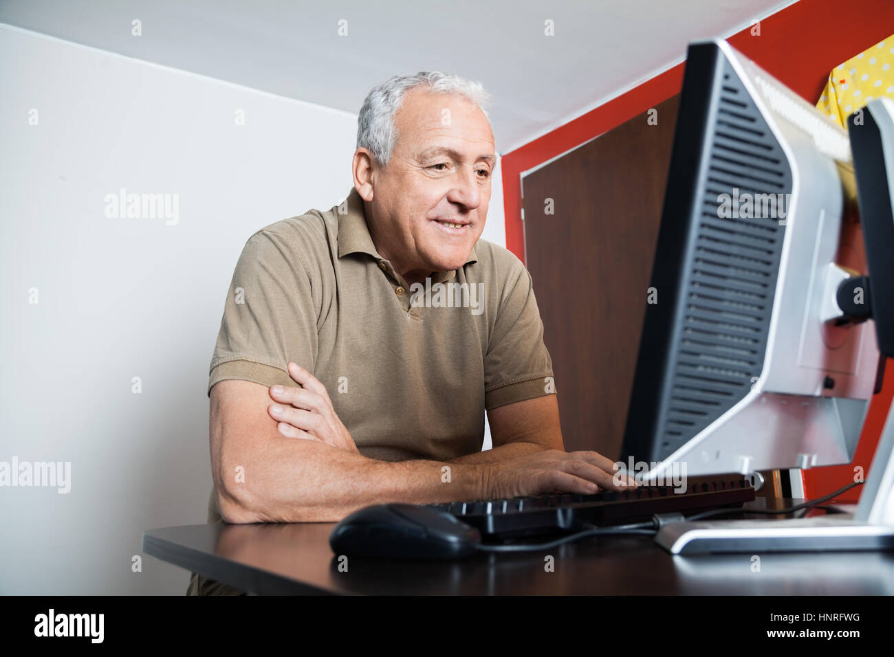 Felice l'uomo senior utilizzando computer in aula Foto Stock