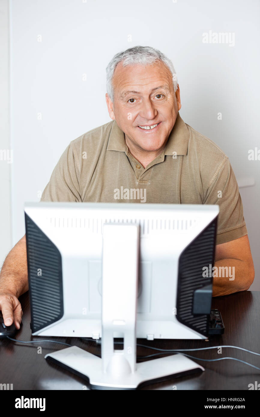 Felice l'uomo senior utilizzando computer in aula Foto Stock