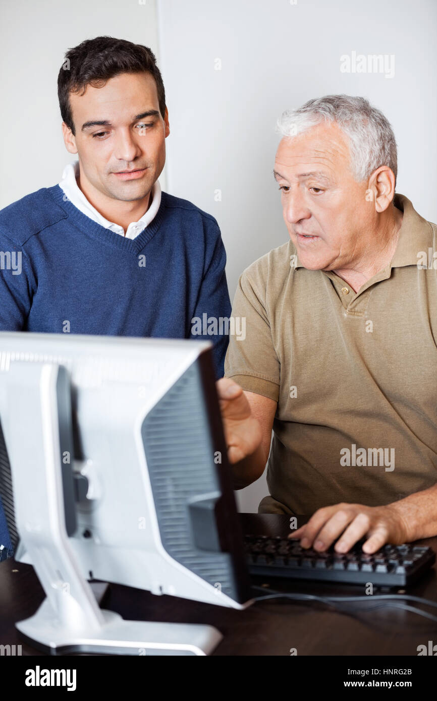 Uomo che parla con insegnante mentre puntando verso il monitor di un computer Foto Stock