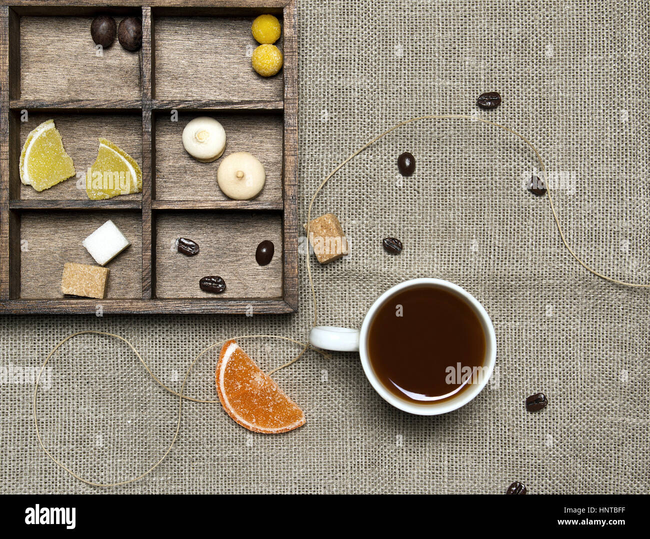 Tazza di caffè, caramelle, i chicchi di caffè su sfondo di lino Foto Stock