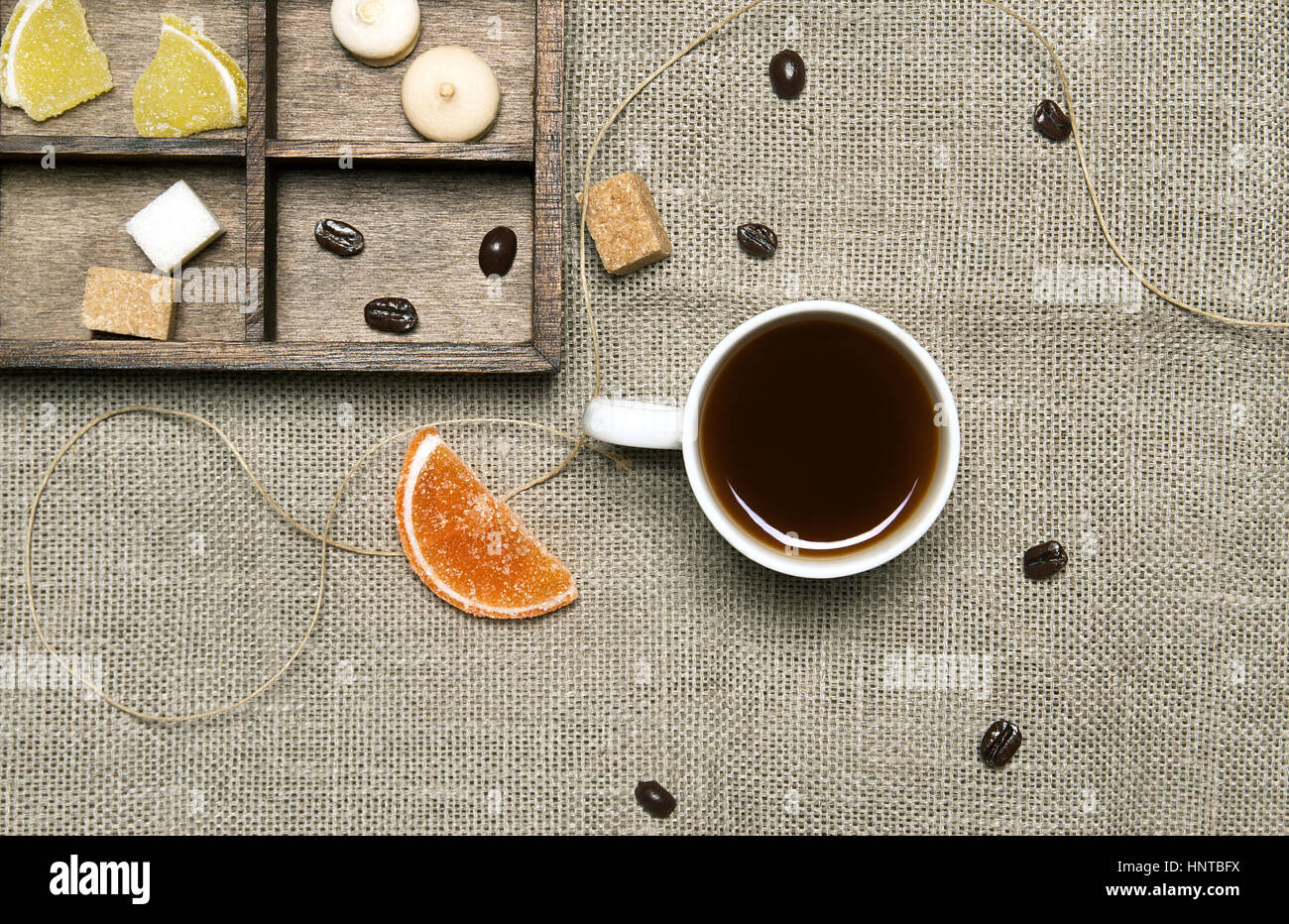 Tazza di caffè, caramelle, i chicchi di caffè su sfondo di lino Foto Stock