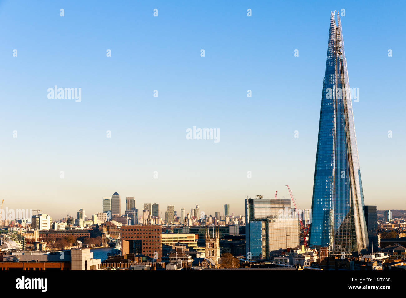 Il quartiere finanziario cityscape di Londra, compresi Canary Wharf e il Coccio contro un blu cielo privo di nuvole Foto Stock