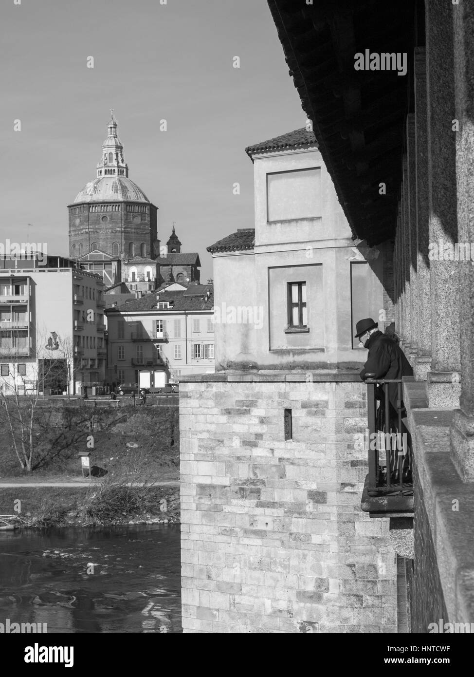 Pavia - Marzo 8, 2015: ponte coperto sul fiume Ticino. Il vecchio uomo con cappello scuro a guardare il fiume che scorre sotto il ponte. Foto Stock