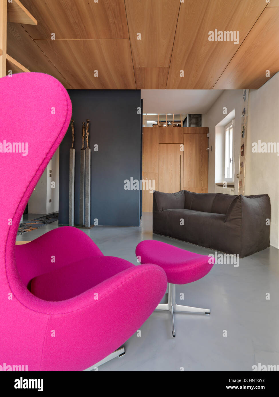 In primo piano del divano viola affacciato sul divano nel soggiorno moderno con pavimento in calcestruzzo Foto Stock