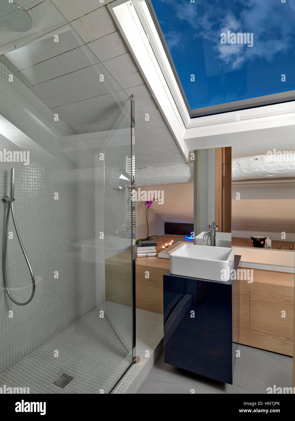 Vista interna di una moderna stanza da bagno in mansarda con box doccia in vetro e bancone lavandino Foto Stock