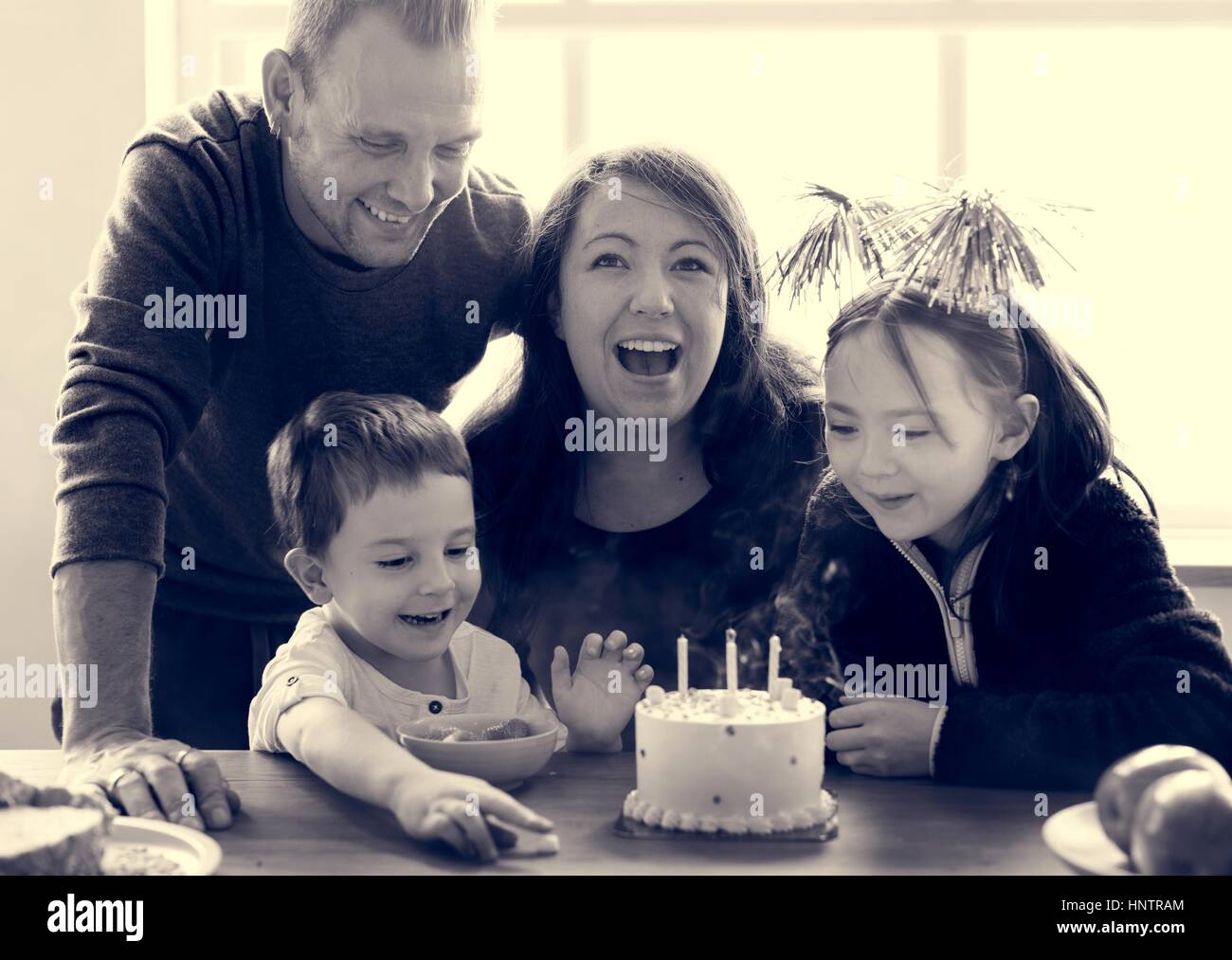 Famiglia festeggia il compleanno torta sorriso felice Foto Stock