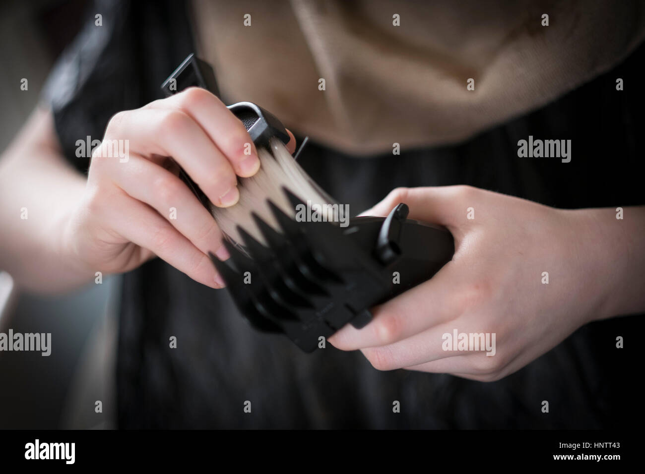 Un ragazzo avente il suo taglio di capelli con clippers e forbici. Foto Stock