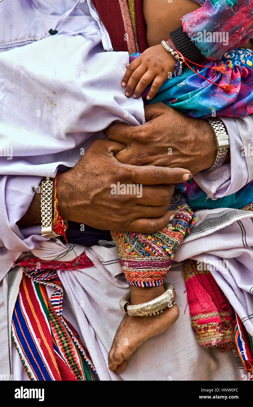 Mani e gambe del padre e figlio, dal villaggio di interni di Kachchh, India, indossando abiti tradizionali e ornamenti Foto Stock