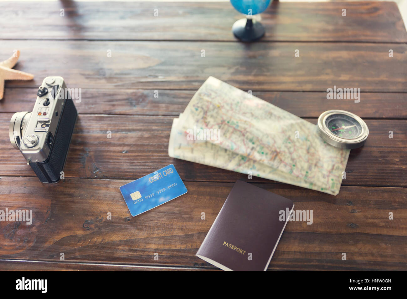 Bussola, passaporto e carta di credito, fotocamera, mappa e stelle marine sul tavolo di legno per uso come concetto di viaggio (vintage tono e messa a fuoco selezionata) Foto Stock