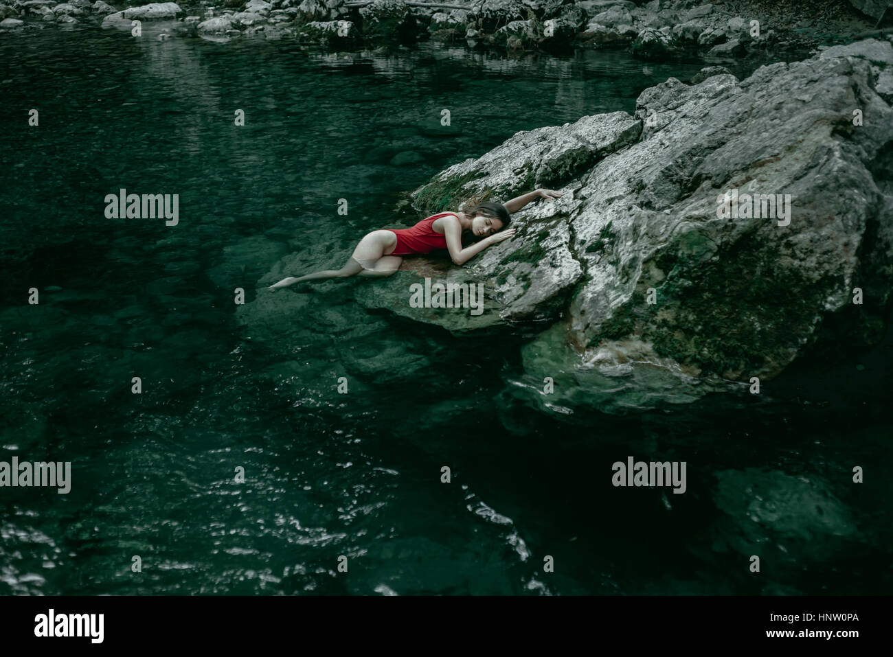 La donna caucasica posa sulle rocce della Piscina di acqua Foto Stock