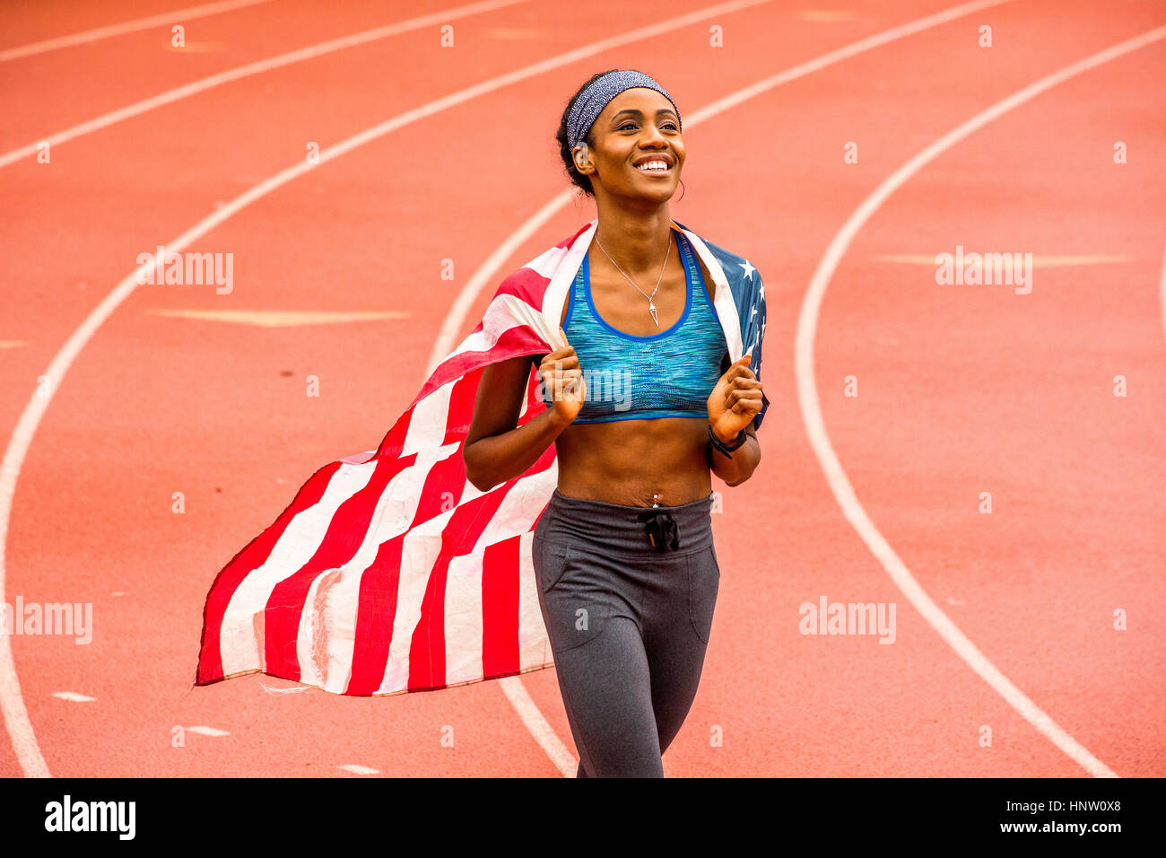 Sorridente atleta nero azienda bandiera americana sulla via Foto Stock