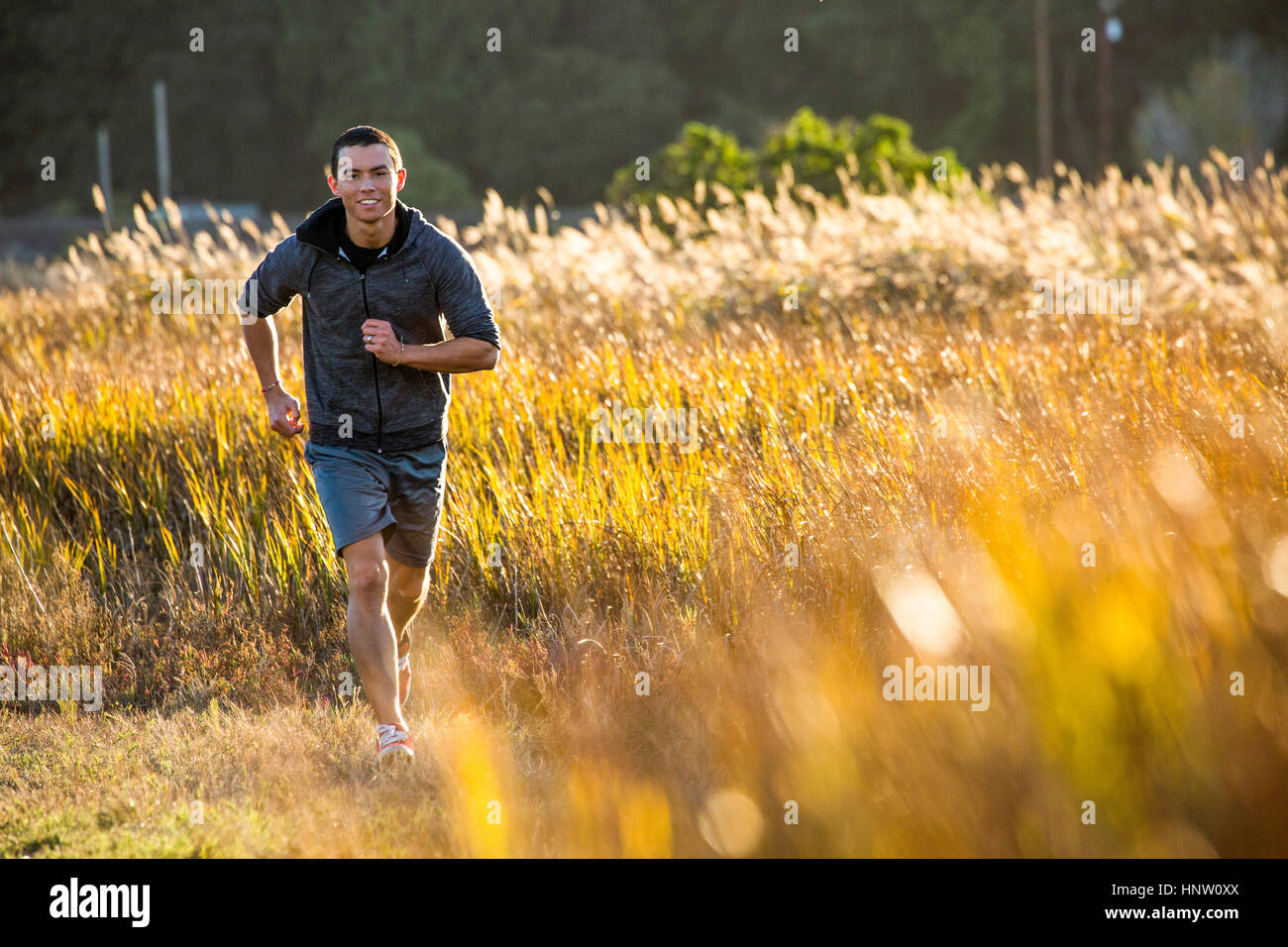 Sorridente razza mista uomo correre nel campo Foto Stock