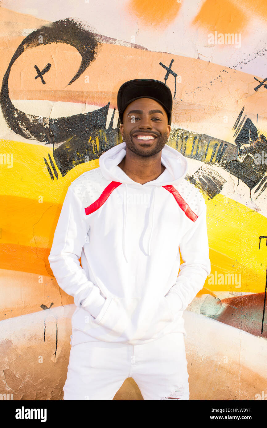 Sorridente uomo nero appoggiato sul muro di graffiti Foto Stock