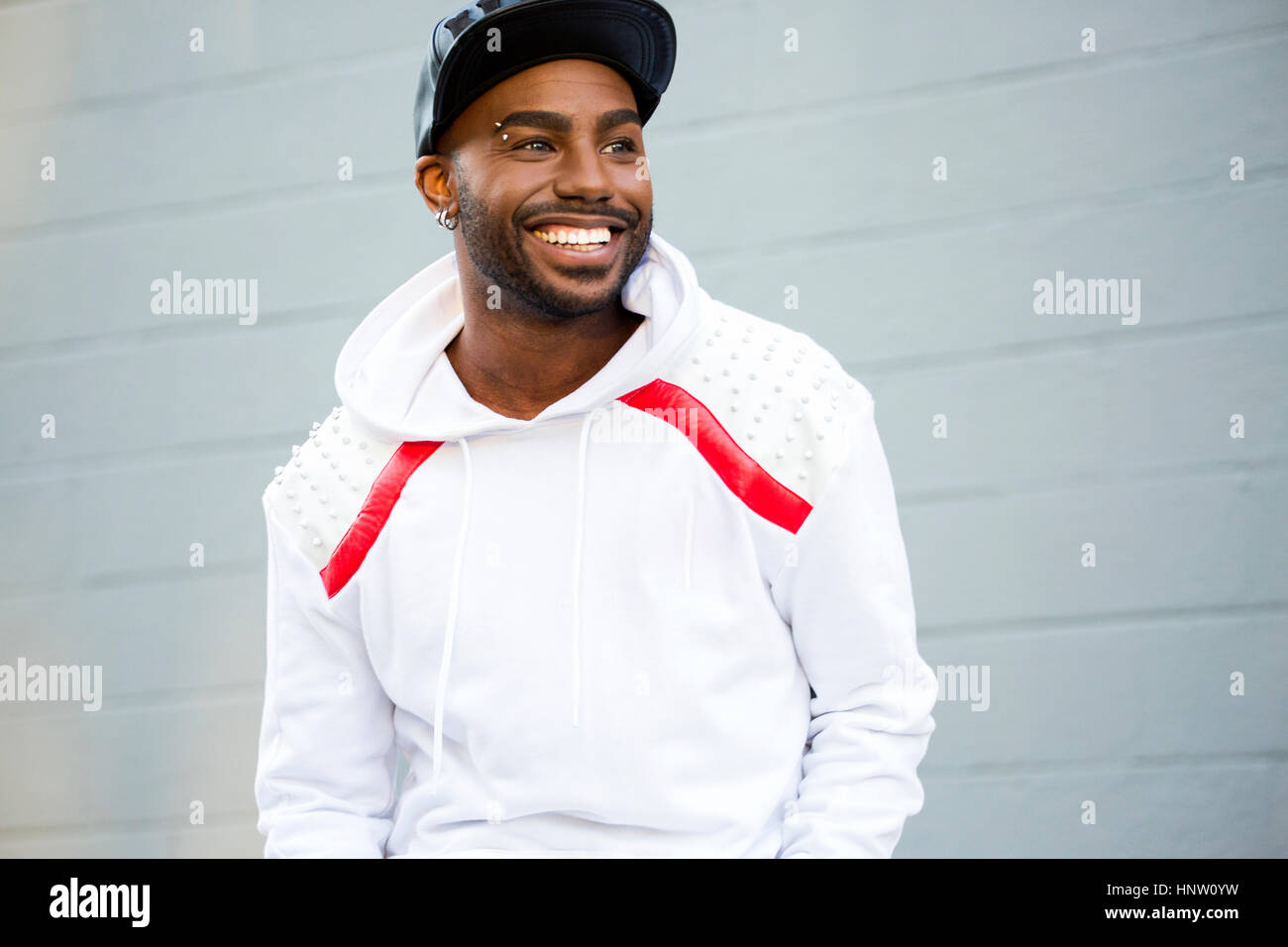 Sorridente uomo nero vicino al muro grigio Foto Stock