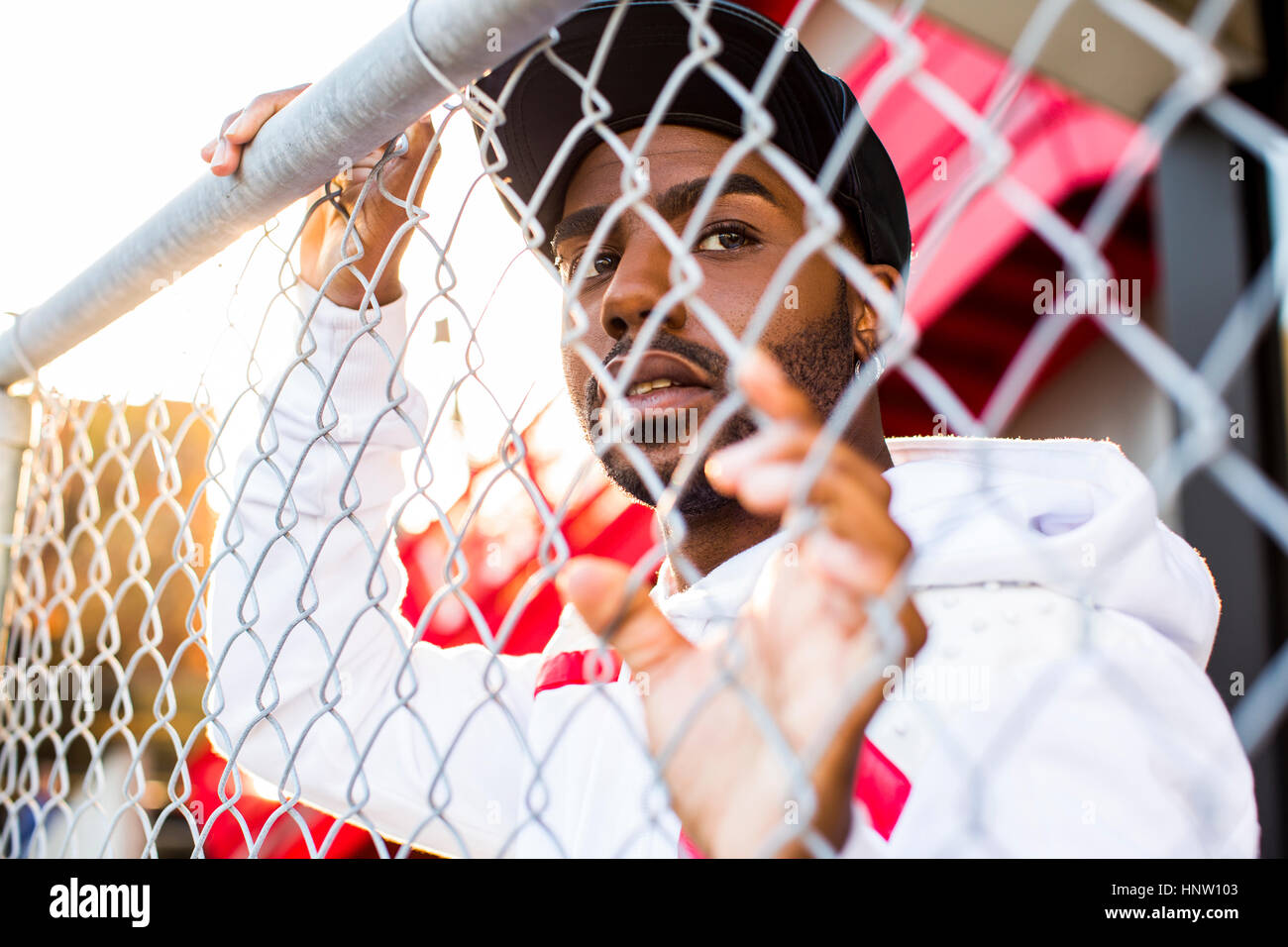 Curioso uomo nero appoggiato sulla catena-recinzione di collegamento Foto Stock