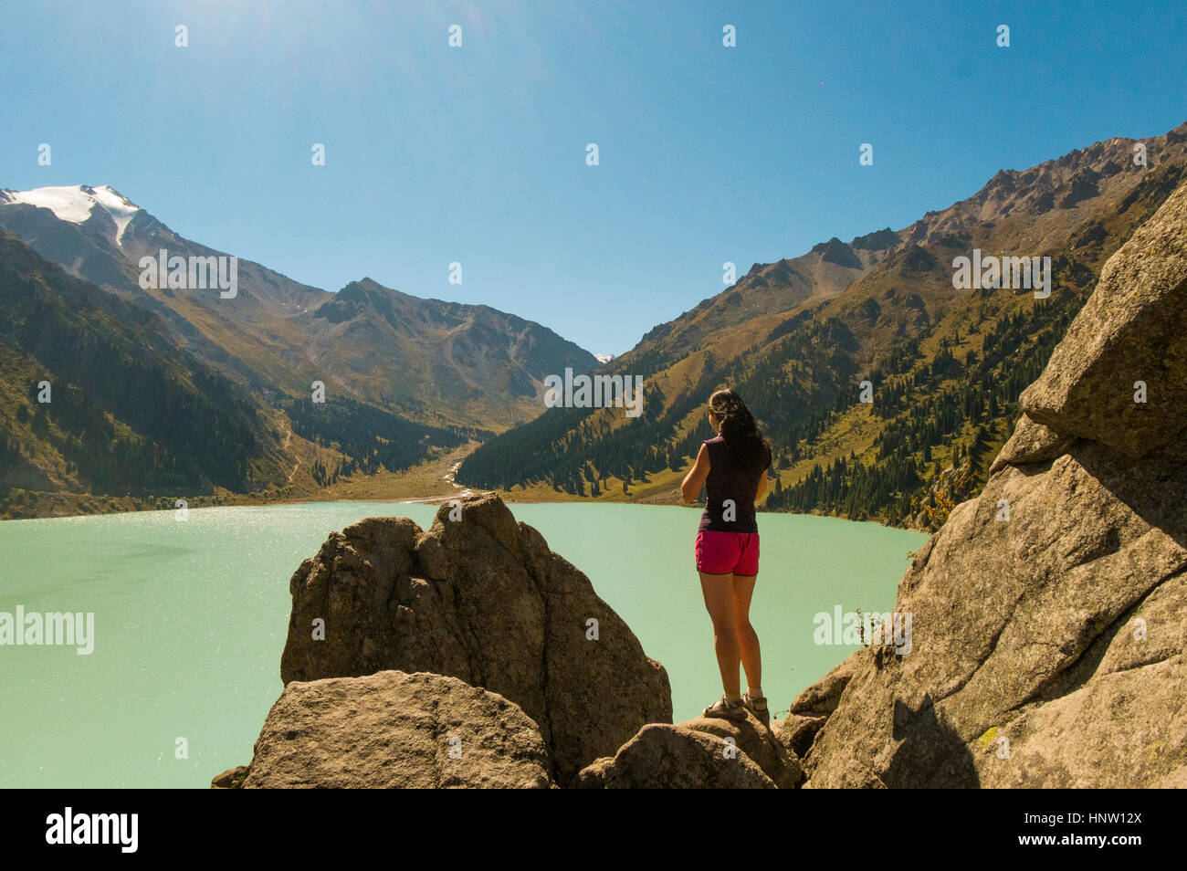 Caucasian donna in piedi su rocce vicino lago di montagna Foto Stock