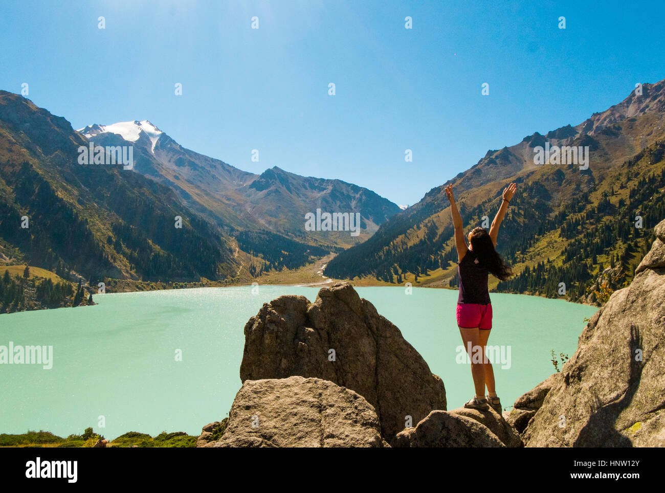 La donna caucasica celebrando su rocce vicino lago di montagna Foto Stock