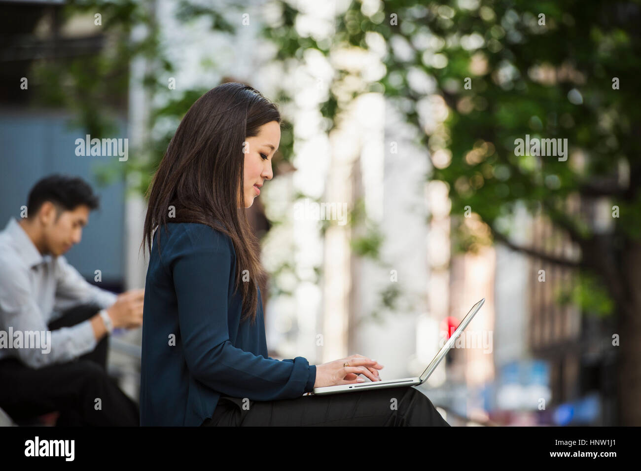 Imprenditrice cinese digitando su laptop in città Foto Stock