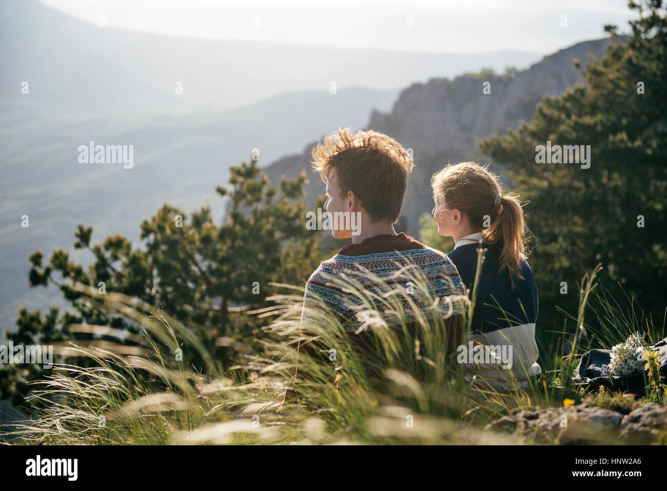 Caucasian giovane seduto sulla collina ammirando vista panoramica Foto Stock