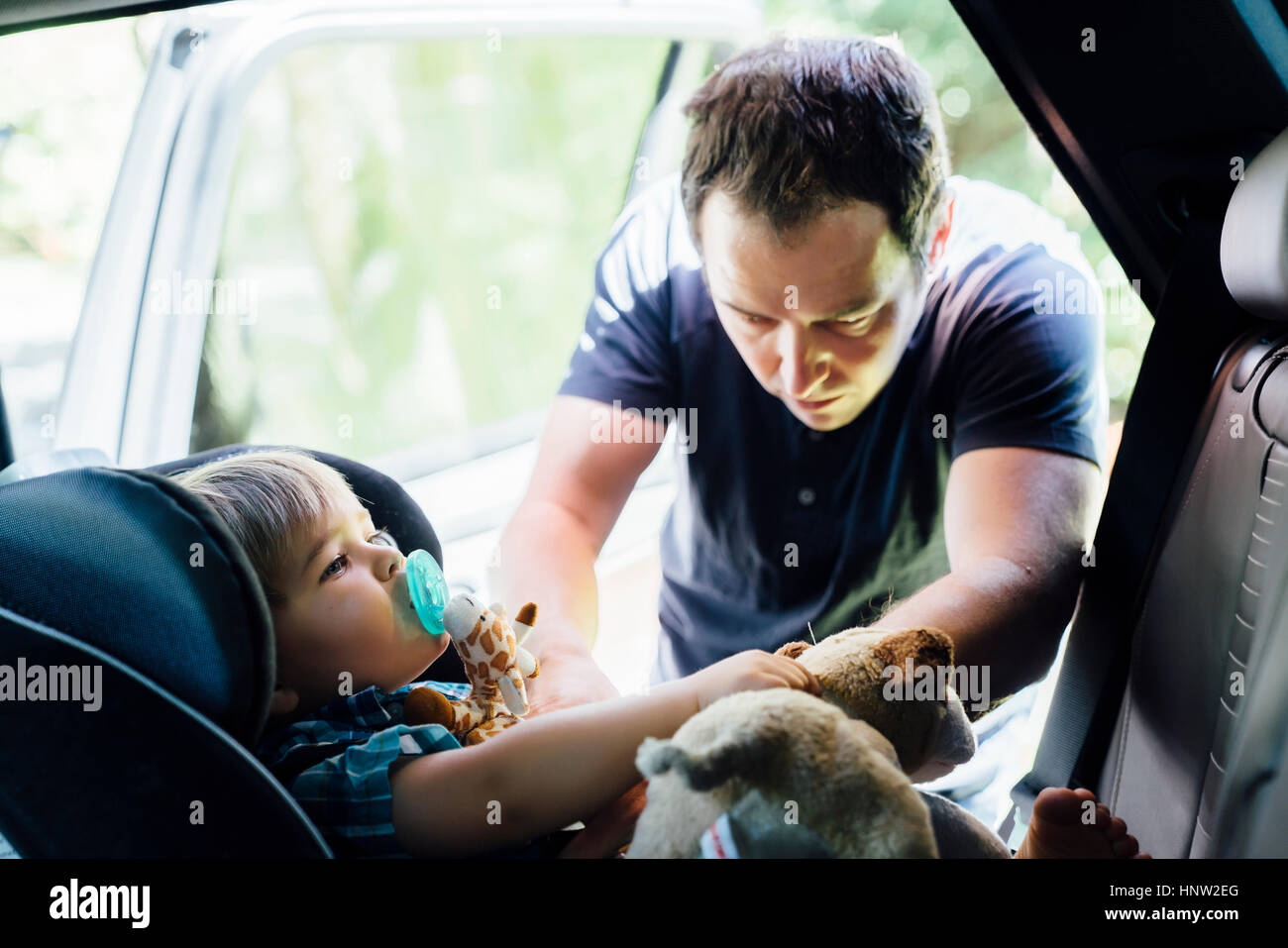 Padre imbozzamento figlio nel seggiolino per auto Foto Stock