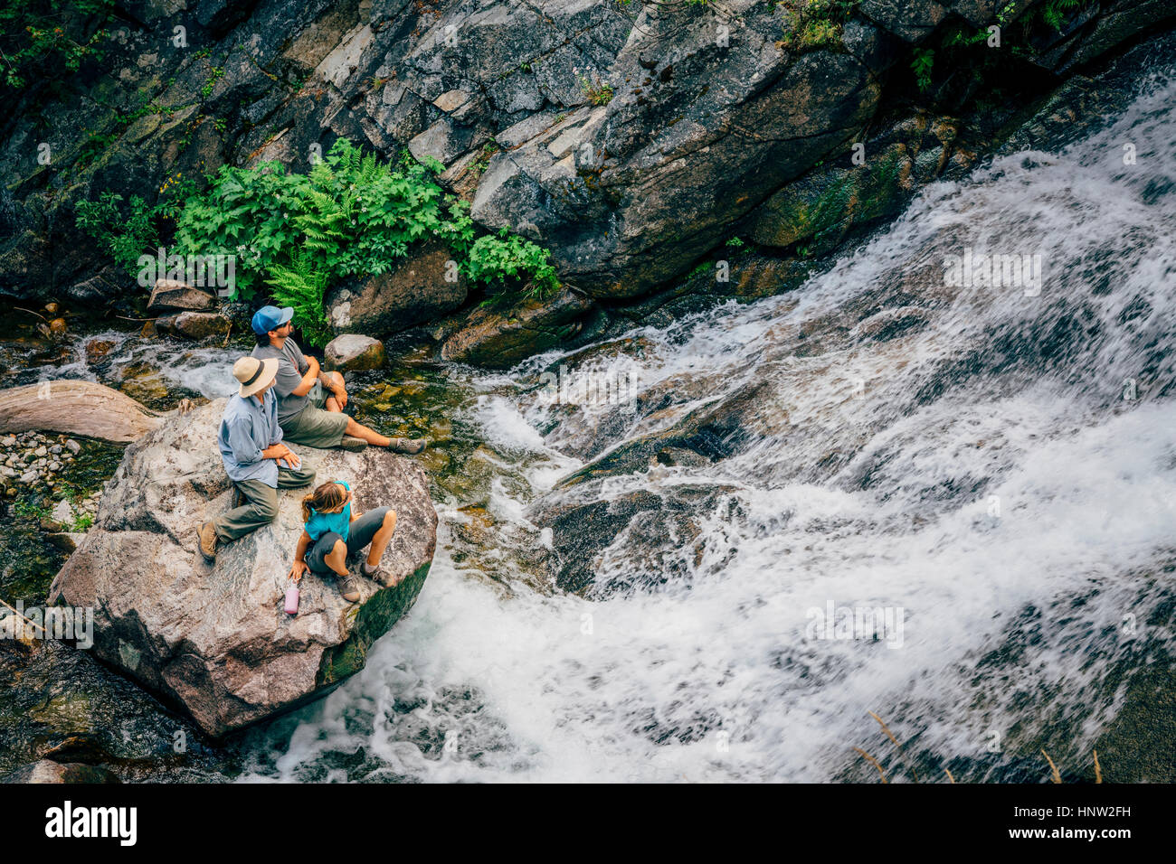 Caucasian gente seduta sulla roccia a guardare le rapide del fiume Foto Stock