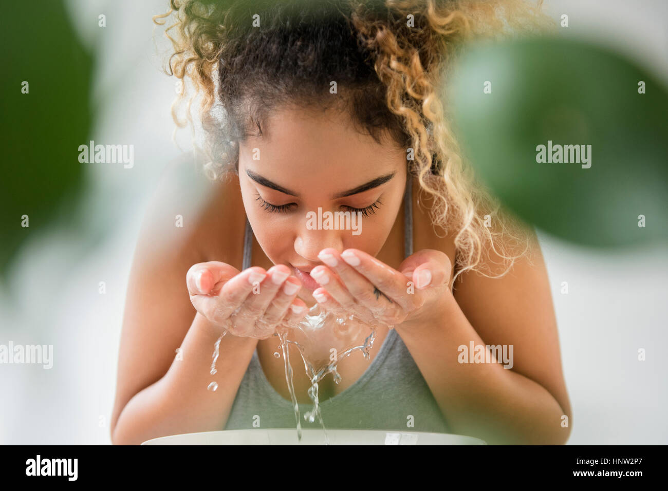 Razza mista donna gli spruzzi di acqua sulla faccia Foto Stock