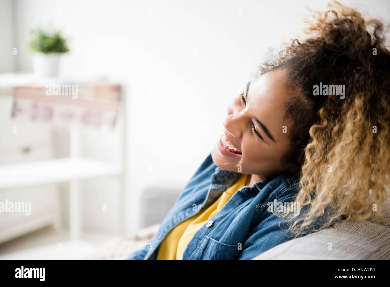 Razza mista donna ridere sul divano Foto Stock