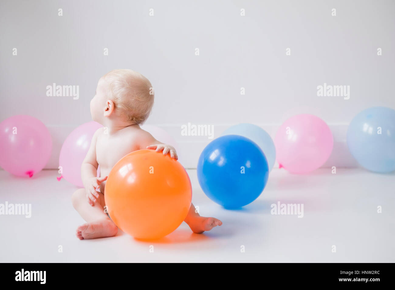 Caucasian bambino seduto sul pavimento con palloncini Foto Stock