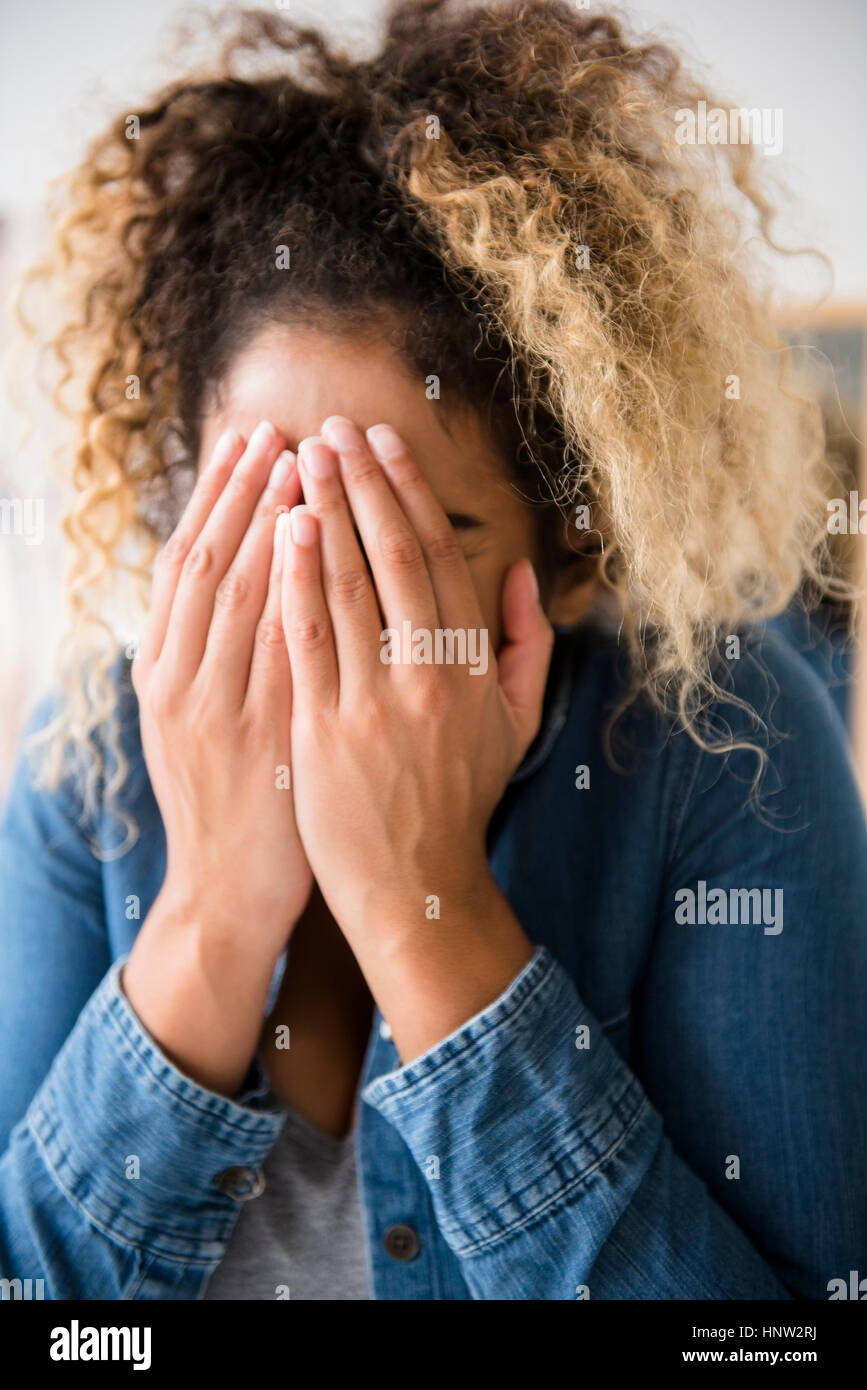 Razza mista donna che ricopre la faccia con le mani Foto Stock