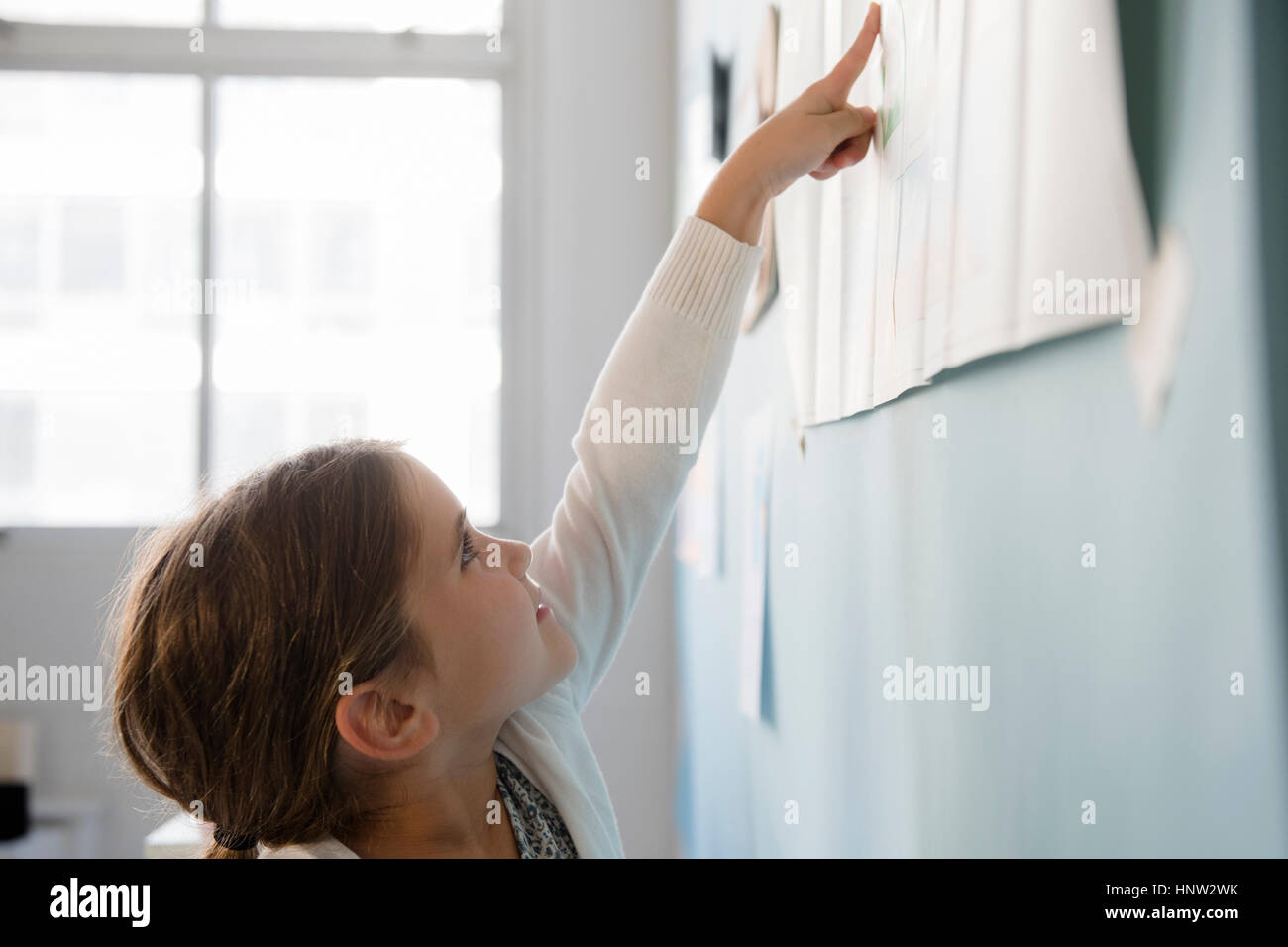 Ragazza caucasica puntando alla carta sulla parete Foto Stock