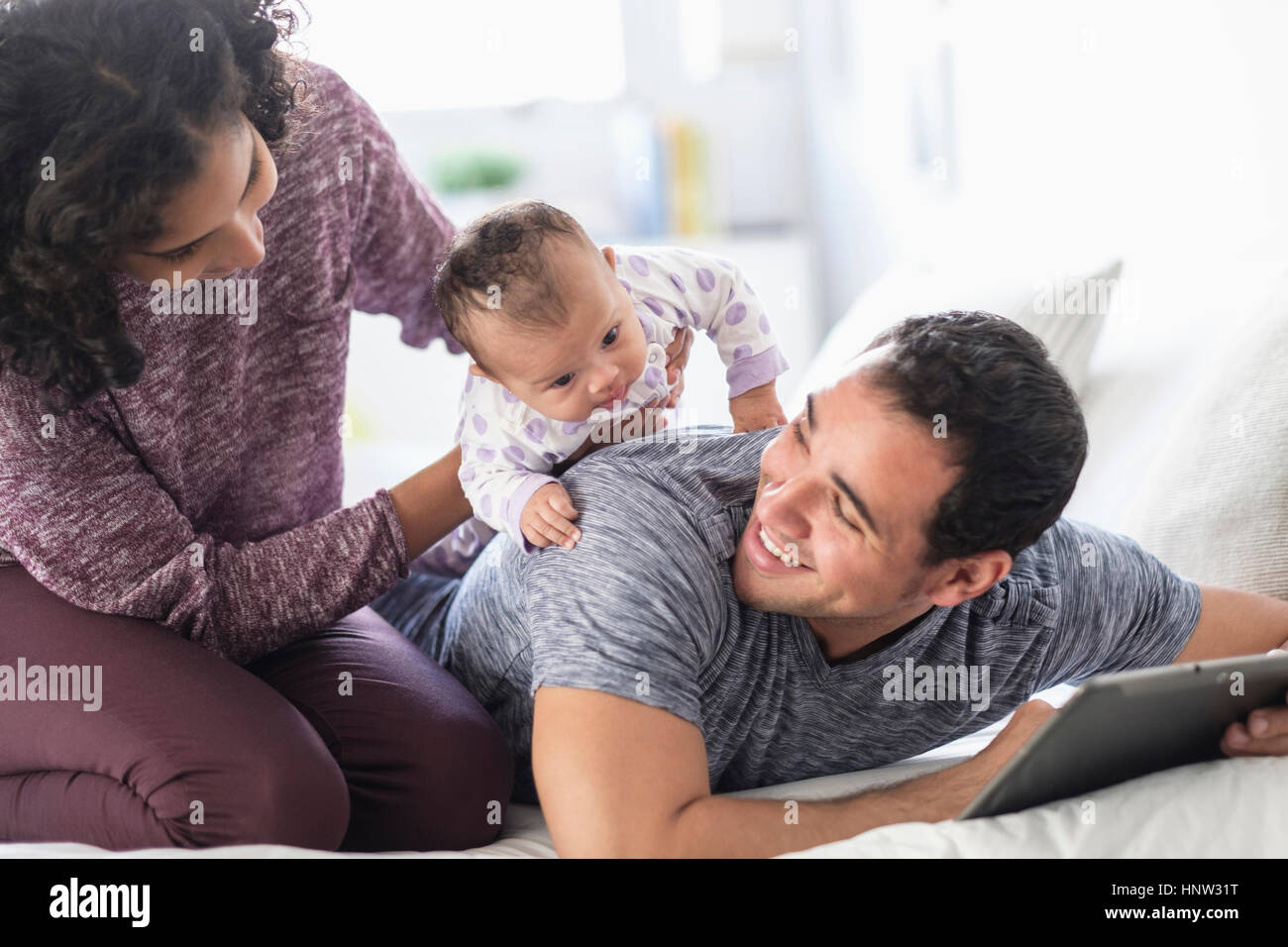 Madre ispanica holding baby figlia sul retro del padre Foto Stock