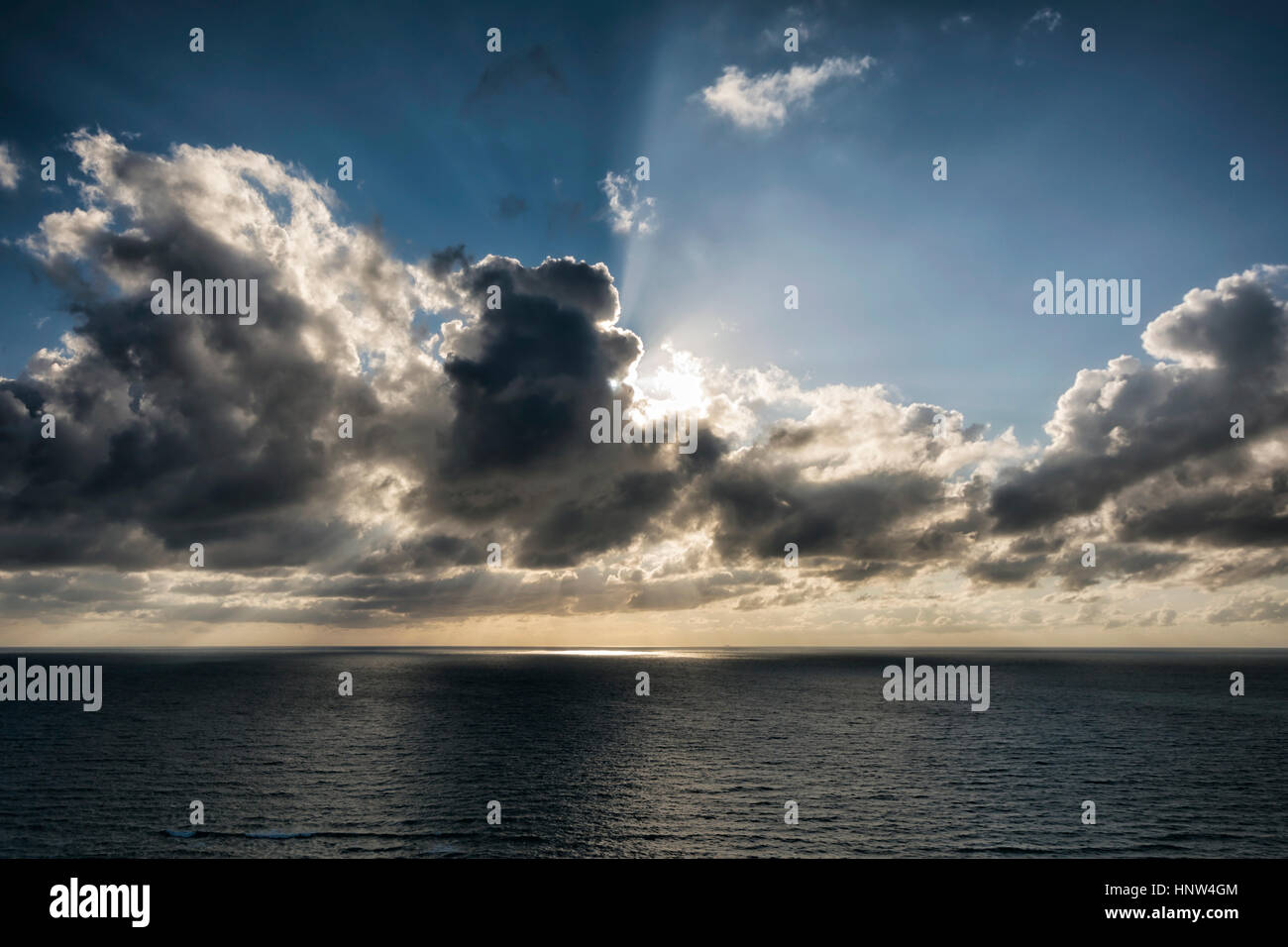 Raggi di sole dietro le nuvole sull'oceano Foto Stock