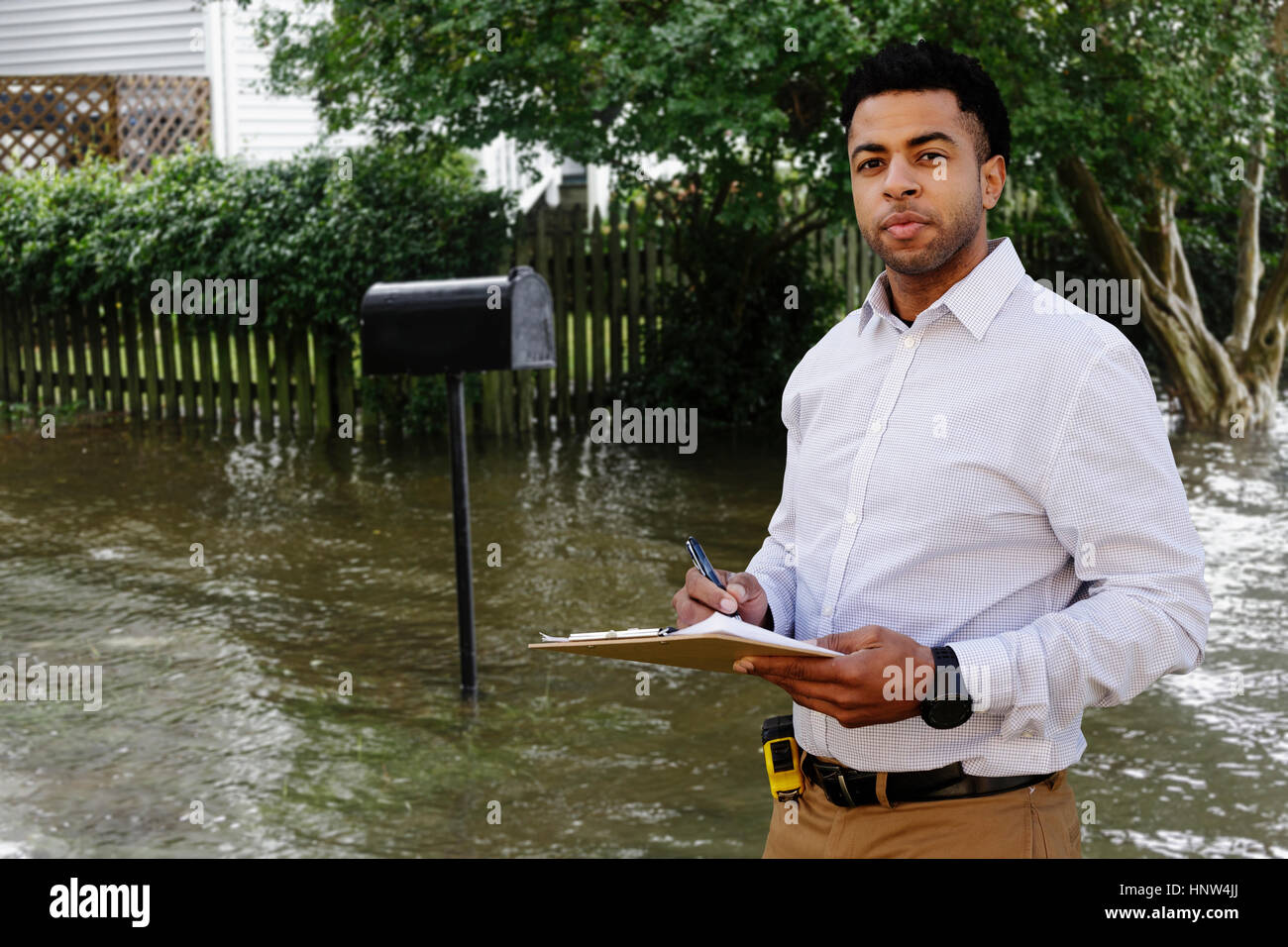 Nero regolatore di assicurazione esaminando le inondazioni danni a casa Foto Stock